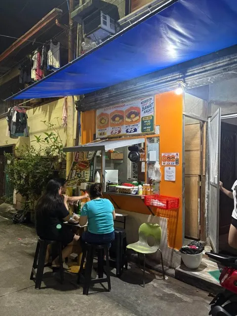 The Hulo stall at night under its blue awning, with customers at the outdoor tables