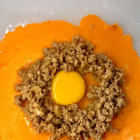 All Meat empanada before folding: a ring of Ilocos longganisa around a raw egg