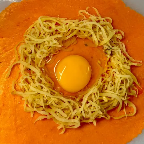 Regular empanada before folding: papaya and a raw egg on orange dough