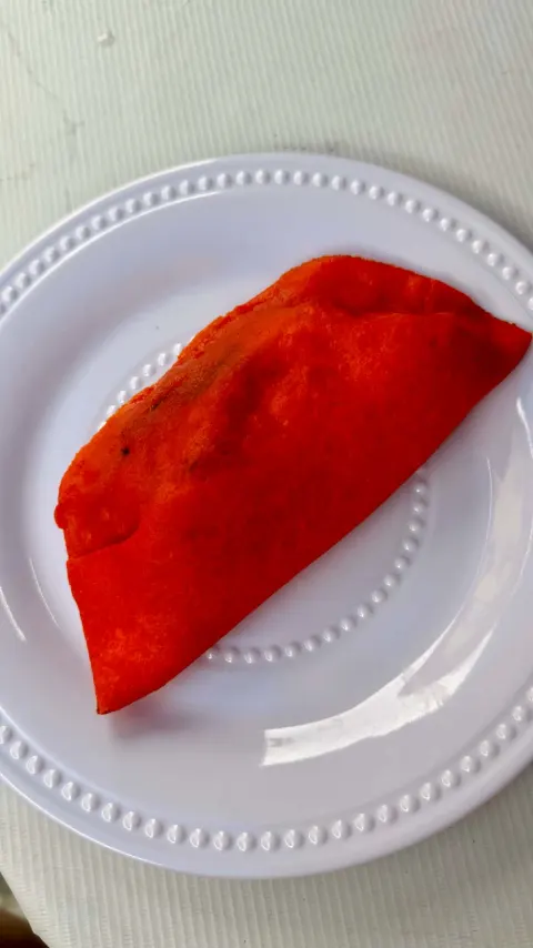 A whole fried orange empanada on a white plate